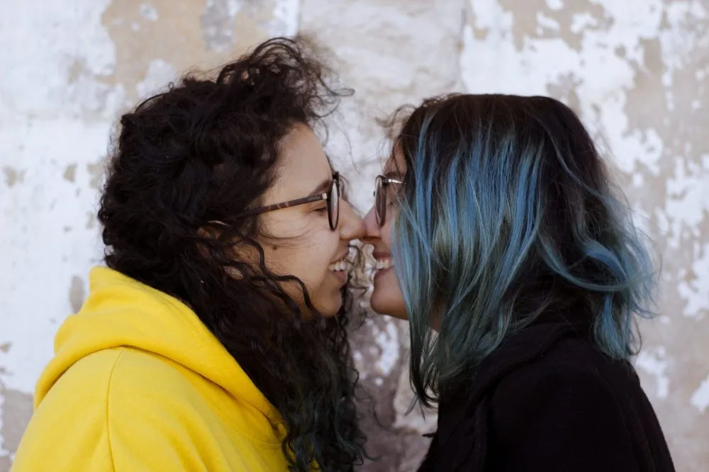 duas mulheres se olhando e quase se beijando na boca.